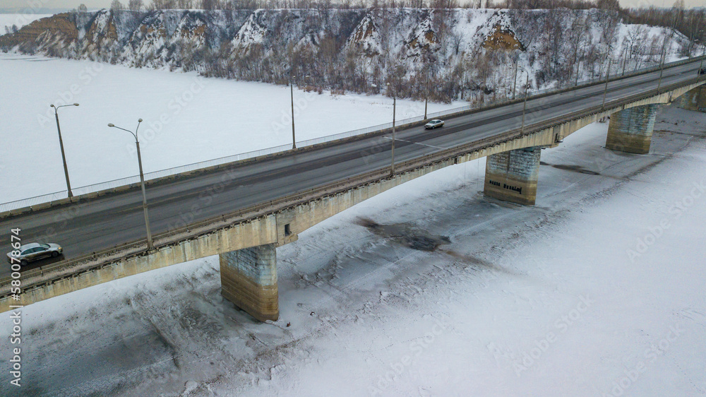 Car bridge over frozen river aerial drone view. Winter transport theme