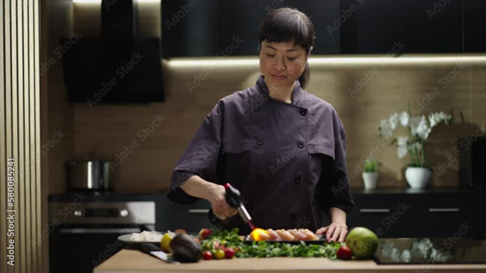 Professional sushi chef preparing roll via fire at commercial kitchen, close-up. Slow-motion shot Professional sushi chef preparing roll via fire at commercial kitchen, close-up. Slow-motion shot