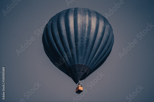 Big dark blue balloon in the sky. Aerostat. People in the basket. Fun. Summer entertainment. Romantic adventures.