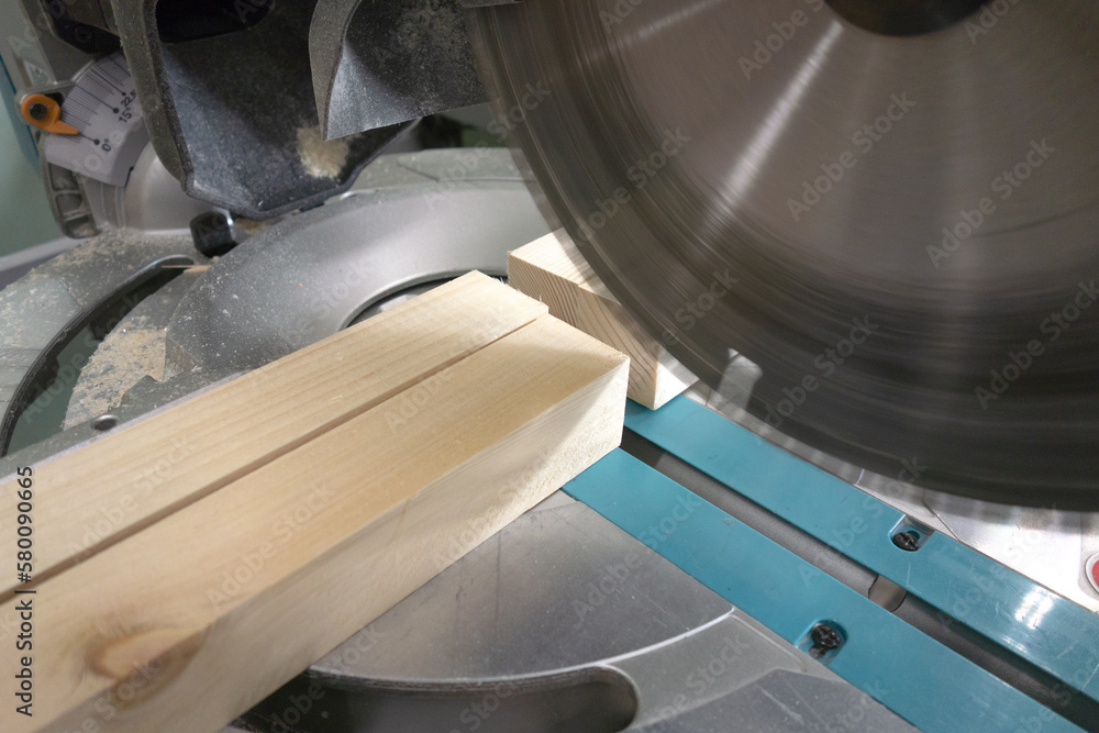 Sawing wooden bars on a miter saw. Cut the boards to size with a saw
