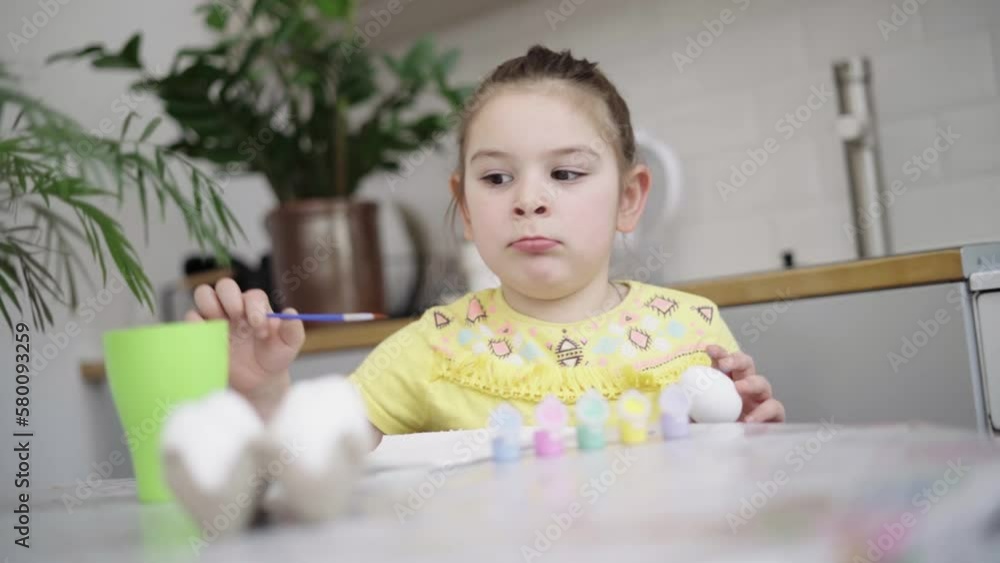 Child girl of preschool age painting Easter eggs at home kitchen. Easter spring traditions. Slow motion Child girl of preschool age painting Easter eggs at home kitchen. Easter spring traditions. Slow motion
