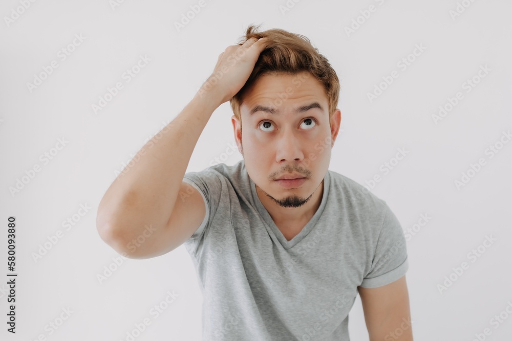 Asian man in grey t-shirt looking at his dyed hair doubtfully isolated on white. Asian man in grey t-shirt looking at his dyed hair doubtfully isolated on white.