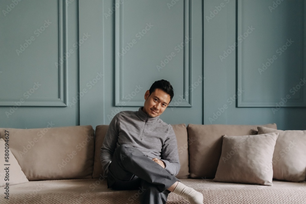 Asian man in fleece sitting in the living room in cold weather. Asian man in fleece sitting in the living room in cold weather.