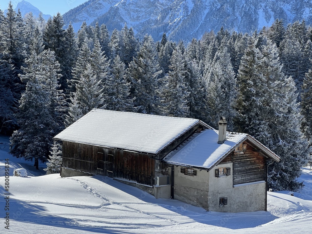 Old traditional swiss rural architecture and alpine livestock farms in the winter ambience of the tourist resorts of Valbella and Lenzerheide in the Swiss Alps - Canton of Grisons, Switzerland