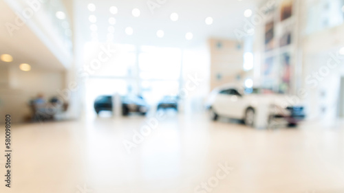 Blurred abstract dealership store, with defocused cars, clients and staff with  soft lightning