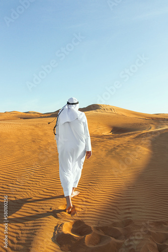 Arabian sheikh in long white dress closeup in the middle of Dubai desert.