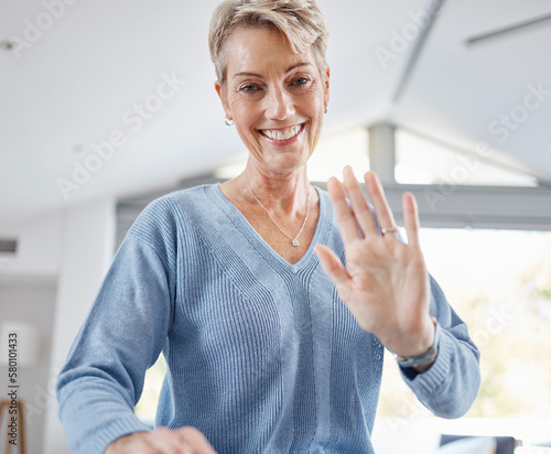 Senior woman, hand and waving on video call, house zoom conference or social networking communication in house or Canada home. Portrait, smile and happy retirement elderly with hello greeting gesture