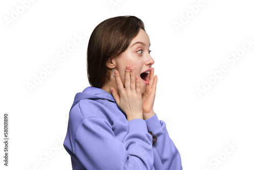 Fotografie The girl is amazed in excitement on a light background, her hands on her cheeks, her mouth open