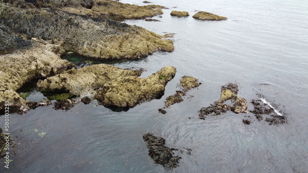 Rocky seashore, top view. Big rocks in the water. Seascape. Brown rock formation on body of water Rocky seashore, top view. Big rocks in the water. Seascape. Brown rock formation on body of water