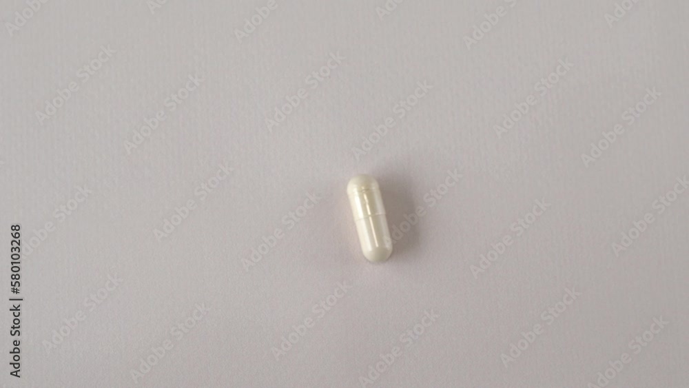 Light capsule of supplements, vitamins, minerals or trace elements in a woman's hand on a beige background. Medication and homeopathy Light capsule of supplements, vitamins, minerals or trace elements in a woman's hand on a beige background. Medication and homeopathy