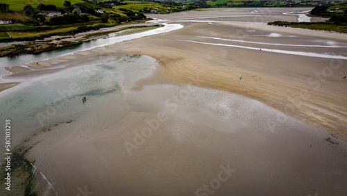 Picturesque southern Irish sandy beach of Inchydoney at low tide on a cloudy day, top view. The coastline of the island of Ireland. Beautiful green hills on the Atlantic Ocean.