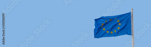 Banner with a blue with stars in circle flag of the European Union (EU) and at blue sky, with copy space, details, closeup