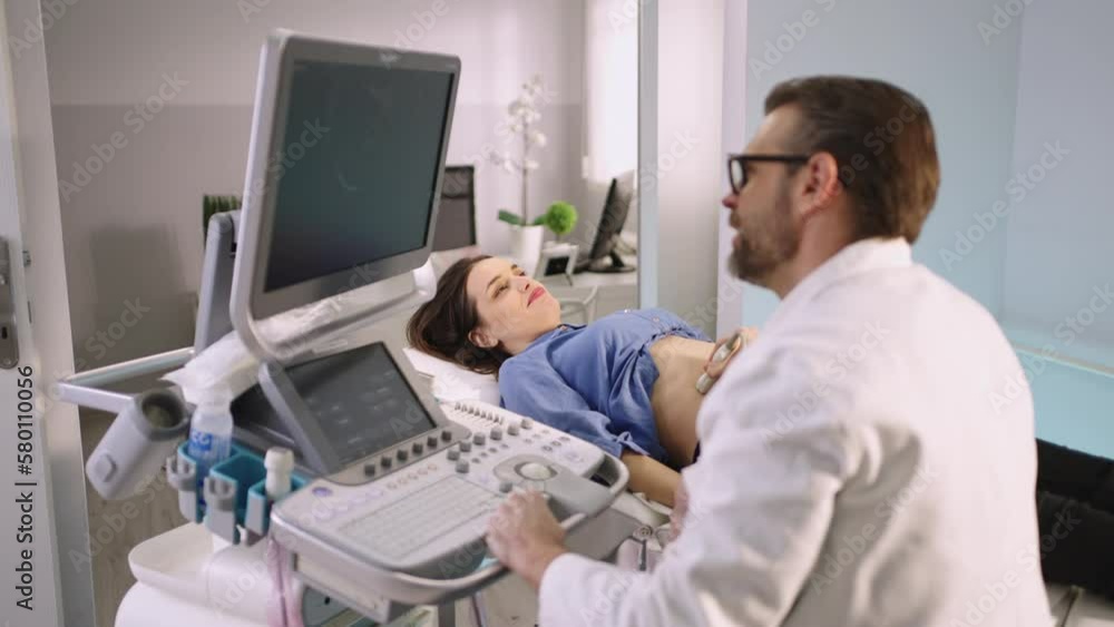 Beautiful smiling woman getting ultrasound from doctor. Clip of a mid adult woman having abdominal ultrasound in hospital Beautiful smiling woman getting ultrasound from doctor. Clip of a mid adult woman having abdominal ultrasound in hospital