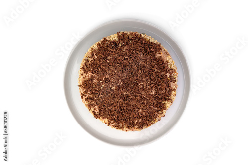 A chocolate biscuit cake with layers of boiled condensed milk and meringue glazed chocolate cream and milk chocolate chips on a plate on a white background. Top view.