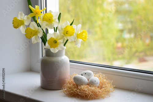 Spring arrangement on the window of daffodil flowers in a vase and Easter eggs.