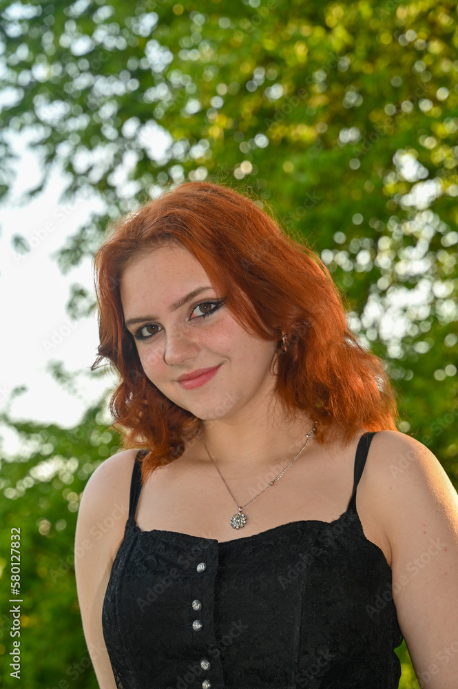 A pretty young redhead woman smiling looking ahead in green nature A pretty young redhead woman smiling looking ahead in green nature