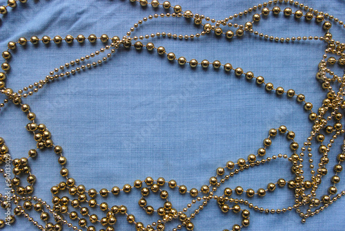 frame of gold beads, garlands on the background of blue denim