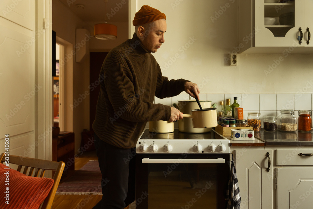 A caucasian man stirring in a saucepan preparing a meal in a kitchen at home. A caucasian man stirring in a saucepan preparing a meal in a kitchen at home.