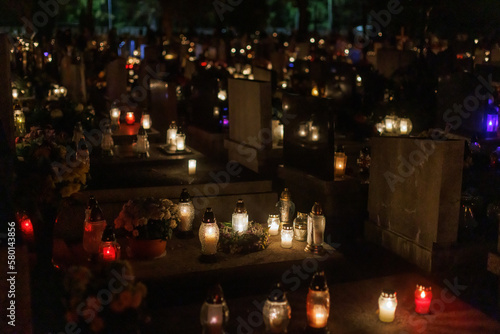 At night in the cemetery celebrating All Hallows' Day with gravestones and candles.