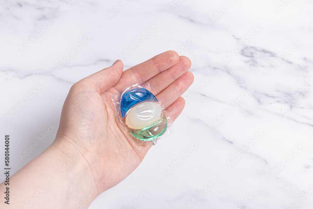 Woman or man holds gel for washing in capsule. Laundry detergent. Space for text Woman or man holds gel for washing in capsule. Laundry detergent. Space for text