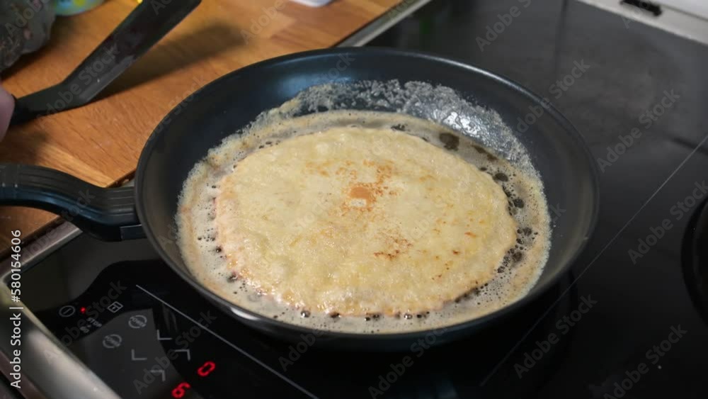 Pancake being picked up from a frying pan
