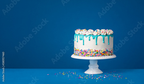 White birthday drip cake with teal ganache over dark blue background