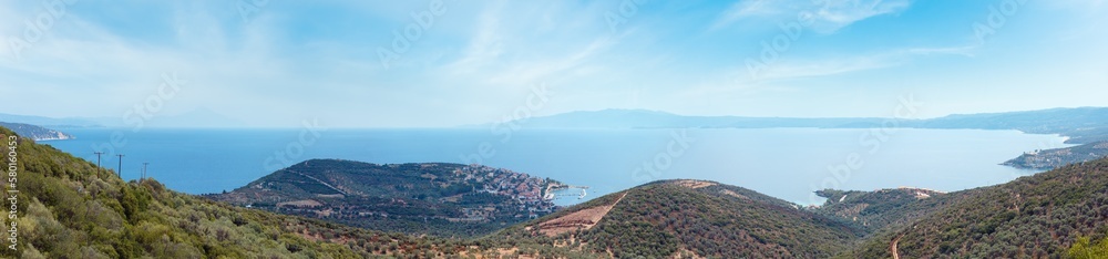 Summer Aegean sea coast top view. The Pyrgadikia village on shore (Sithonia, Halkidiki, Greece). Athos mount silhouette leftward in far.