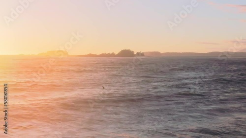 A drone shot over Chesterman beach at sunset with water waves hitting to rocky cliffs photo