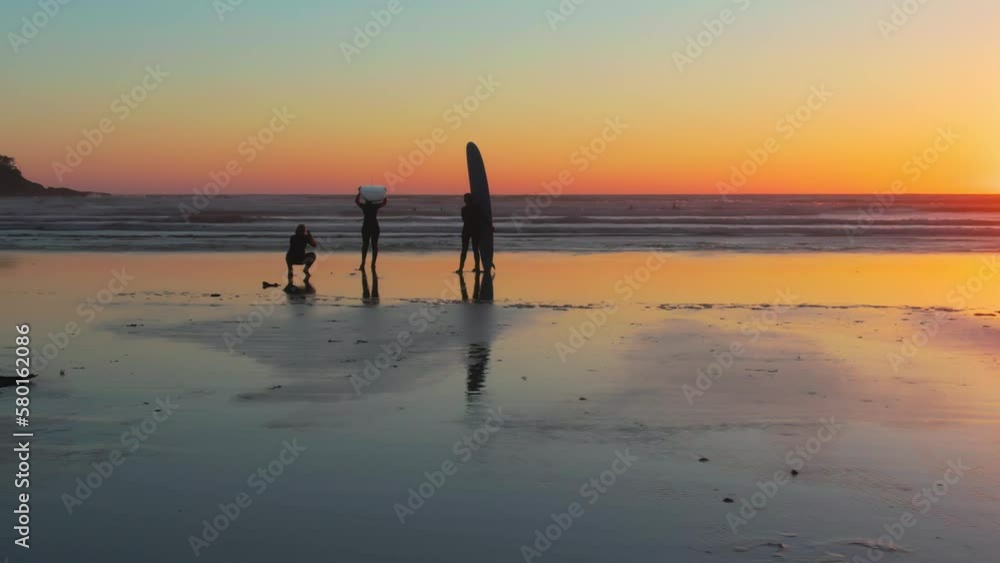 A drone shot of people silhouettes ready for surfing in Chesterman beach at sunset