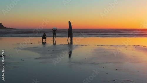 A drone shot of people silhouettes ready for surfing in Chesterman beach at sunset