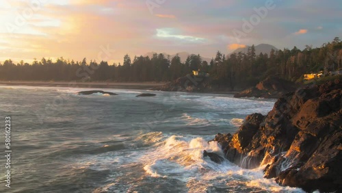 A drone shot over Chesterman beach at sunset with water waves hitting to rocky cliffs photo