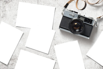 photo mockup / template with vintage analog camera and paper prints / images scattered on a white wooden table, top view / flat lay