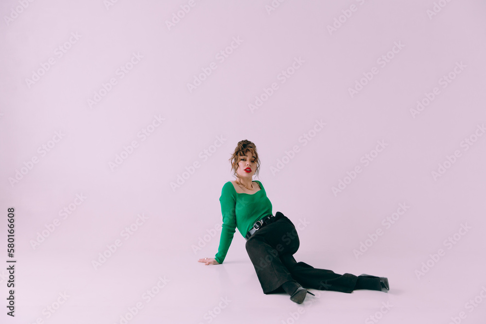 Fototapeta premium A beautiful glamorous girl with a slim figure in sunglasses in a blue jacket and green at a trendy hot stylish fashion photo shoot posing in a photo studio.