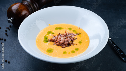 Fresh pumpkin cream soup with fried bacon and oil.