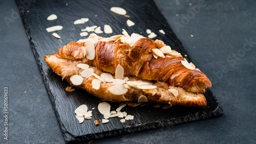 French breakfast fresh croissant with almond on black background.