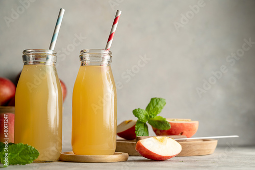 Apple juice glass bottles, with fresh red apples, wooden background. 