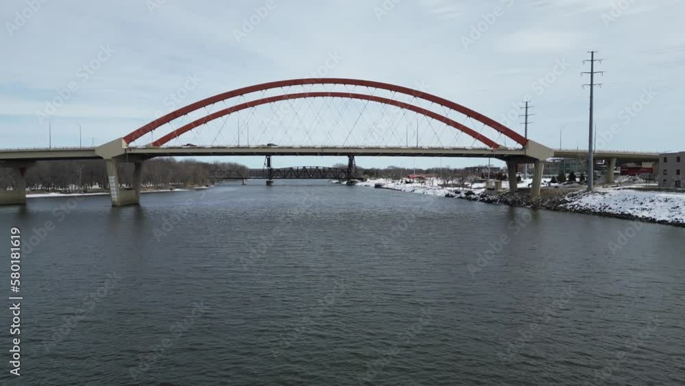 Highway Tied-Arch Bridge with Steel and Concrete over the Mississippi River in the Minnesota Winter with Snow and Cars on the Road and Trees on the Shore Highway Tied-Arch Bridge with Steel and Concrete over the Mississippi River in the Minnesota Winter with Snow and Cars on the Road and Trees on the Shore