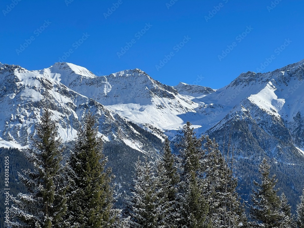 Beautiful sunlit and snow-capped alpine peaks above the Swiss tourist sports-recreational winter resorts of Valbella and Lenzerheide in the Swiss Alps - Canton of Grisons, Switzerland (Schweiz)