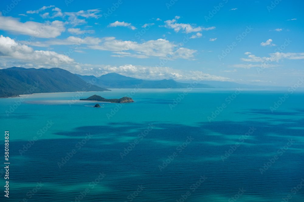 Clear turquoise waters, coral reefs and blue skies with white fluffy clouds along the coastline of Cairns — Coral Sea, Far North Queensland, Australia