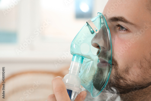 Photography Sick man using inhalation nebulizer indoors, closeup