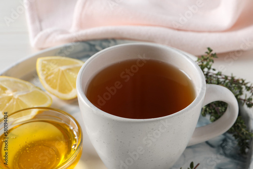 Aromatic herbal tea with thyme, honey and lemons on tray, closeup
