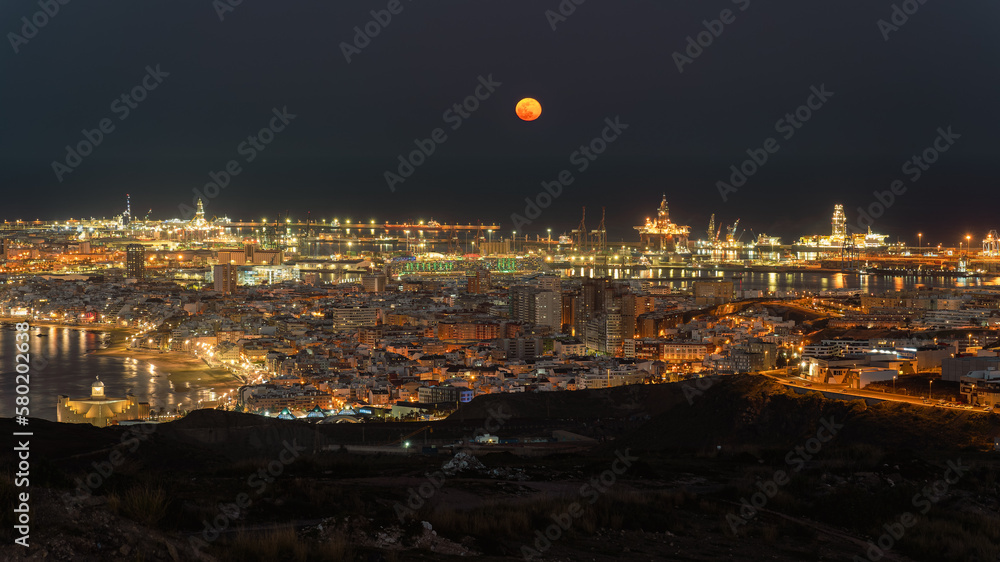 Night view of city and ocean, with orange full moon, Las Palmas de Gran Canaria, Spain