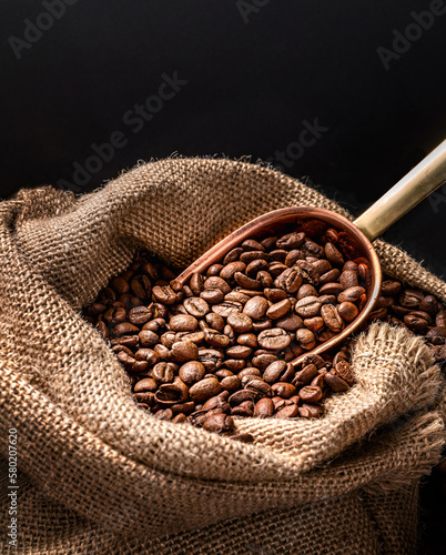 Murais de parede Scoop of coffee beans in a bag on dark board