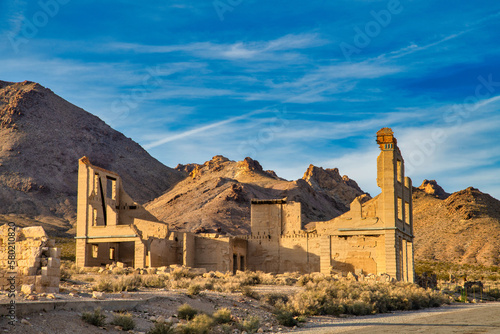Ghost town stone ruins of an old building in a mountainous desert landscape on a clear day.