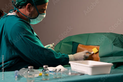 Doctor or surgeon apply betadine to the patient for anesthesia injection to reduce pain before perform surgery operation. Medical surgery preparation procedure in sterile operation theater concept. photo