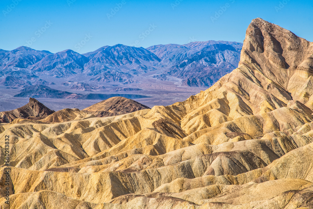 Remote desert mountains and rolling hills with colorful layers of rock on a clear day.