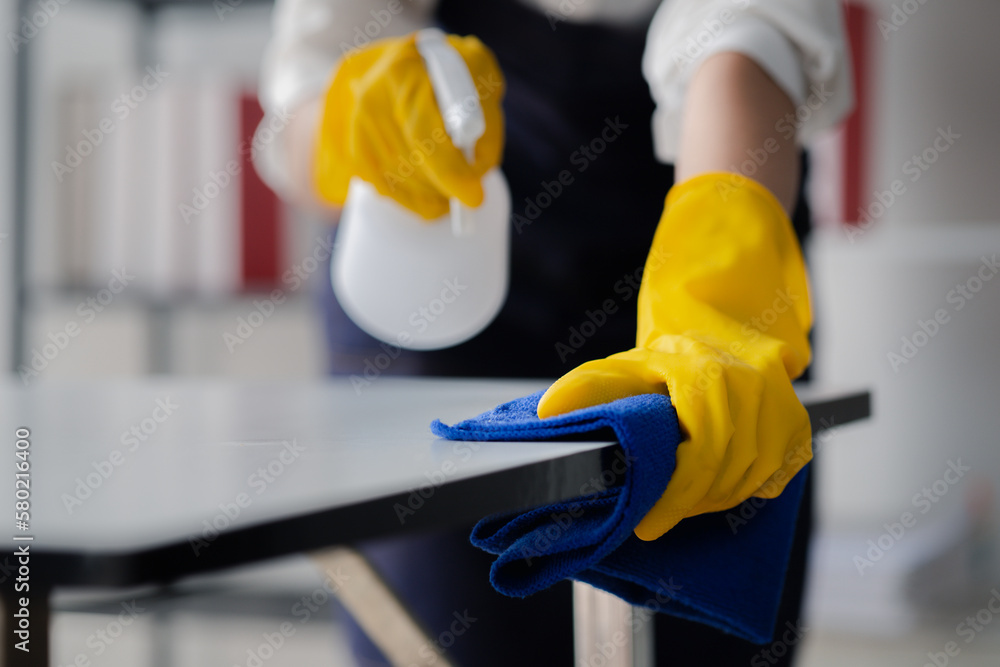 Person cleaning the room, cleaning staff is using cloth and spraying