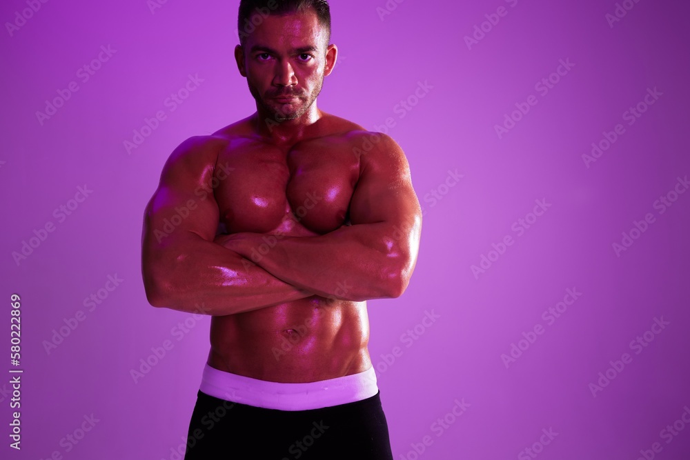 Man athletic body bodybuilder in briefs with nude torso abs full-length in the background fitness classes, purple colored light. Advertising, sports, active lifestyle, competition, challenge concept. Man athletic body bodybuilder in briefs with nude torso abs full-length in the background fitness classes, purple colored light. Advertising, sports, active lifestyle, competition, challenge concept.