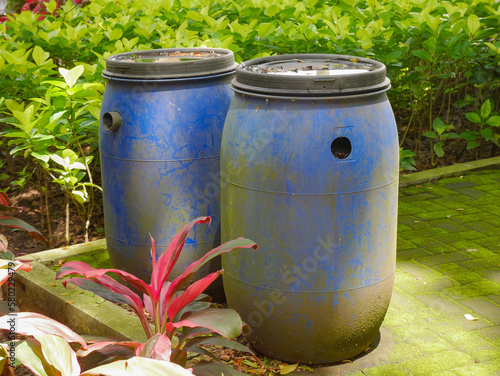 Blue, plastic water barrel reused for collecting and storing rainwater for watering plants