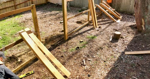 Building a Fence Flying Aerial Drone Shot Two Builders Attach Picket Boards to Backer Rails and Posts Sunny Day Outside